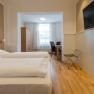 Hotel Unter den Linden E07, © Hotel Unter den Linden Hotelzimmer mit zwei Betten, Fernseher, Tisch und Stühlen.