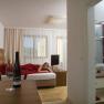 Kitzer Wein Genuss Zimmer, © Johannes Kitzler Ein modernes Hotelzimmer mit einem Bett, auf dem eine Person liegt, und einem Tisch mit einer Weinflasche und einem Glas.