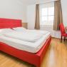 Hotel Unter den Linden 217, © Hotel Unter den Linden Modernes Hotelzimmer mit rotem Bett und Schreibtisch.