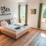 Gästezimmer, © Matthias Auer Modernes Gästezimmer mit Doppelbett, grünen Vorhängen und Wanddekoration im Hubertushof Poysdorf.