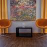 arte Hotel Krems, © Niederösterreich Werbung / Maximilian Pawlikowsky Zwei orangefarbene Stühle vor einem bunten Gemälde und gelben Vorhängen.