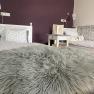 Zweibettzimmer, © Doris Winkler Zweibettzimmer mit lila Wand, zwei Betten, Nachttisch mit Buch und flauschiger Decke.