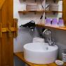Badezimmer, © Doris Winkler Badezimmer mit Waschbecken, Spiegel, Föhn und Holzregalen.