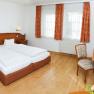 Doppelzimmer im Dreikönigshof, © Hotel Drei Königshof/Henk Ein gemütliches Doppelzimmer mit zwei Betten, Holzmöbeln und einem Schreibtisch mit Stuhl.