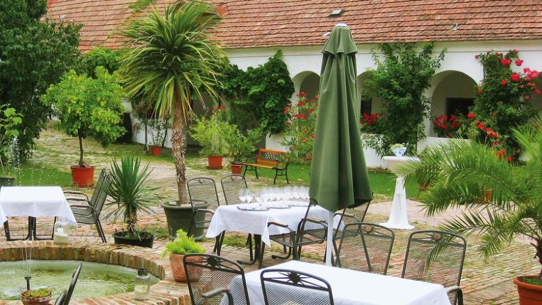 Innenhof, © Genießerhof Haimer Ein idyllischer Innenhof mit Tischen, Stühlen, Pflanzen und einem Brunnen.