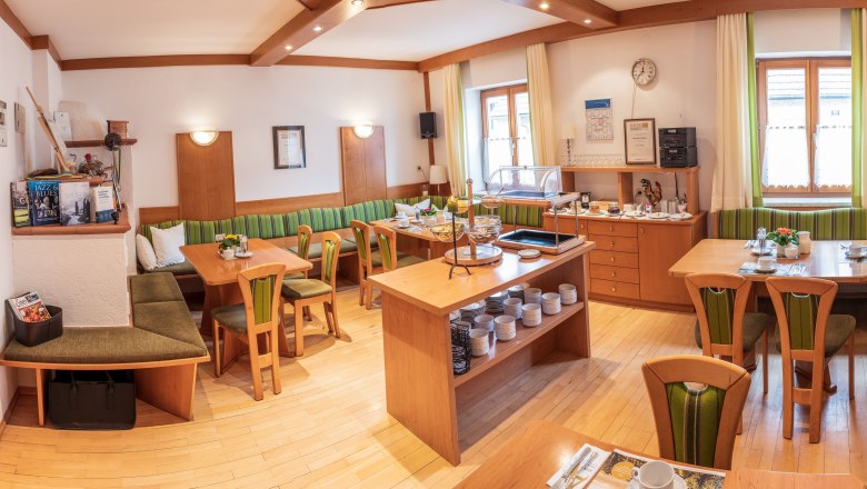 Snídaňová místnost, © Michael Parak Útulná snídaňová místnost s dřevěným nábytkem, prostřenými stoly a bufetem.