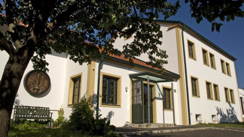 Kitzer wine enjoyment, © Johannes Kitzler Winery with a white façade and green window frames, surrounded by trees.