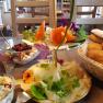 Frühstück, © Doris Winkler Ein gedeckter Frühstückstisch mit Brötchen, Käse, Joghurt mit Beeren und dekorativen Blumen.