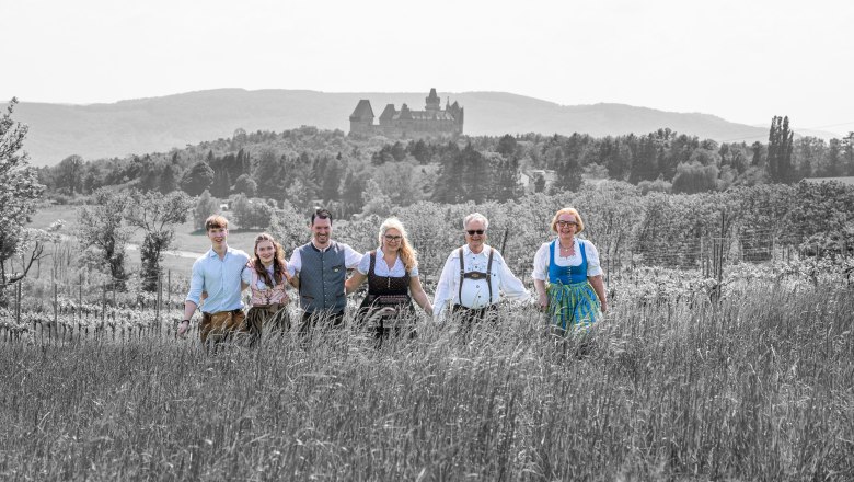 TDR-Hopfeld-Dreikönigshof, © ehnpictures- Johannes Ehn A group of six people in traditional dress stand in a field with a castle in the background.