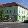 Weinhotel Rieder, © Familie Rieder Grünes Gebäude mit Hotel- und Café-Schildern an einer Straßenecke.