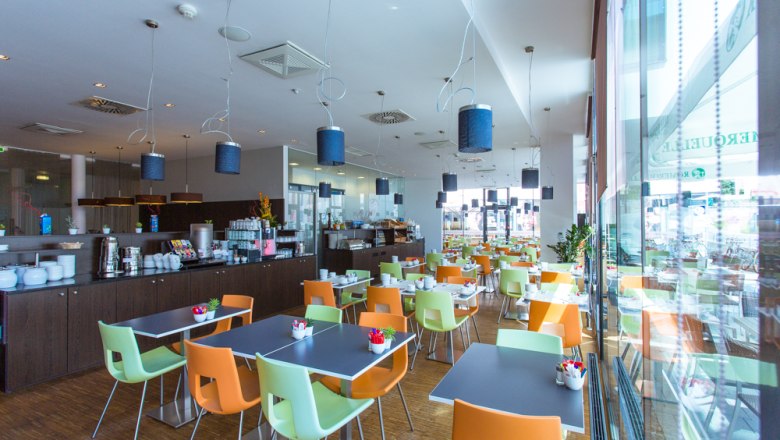 Frühstücksraum, © arte Hotel Krems Moderner Frühstücksraum mit bunten Stühlen und gedeckten Tischen.