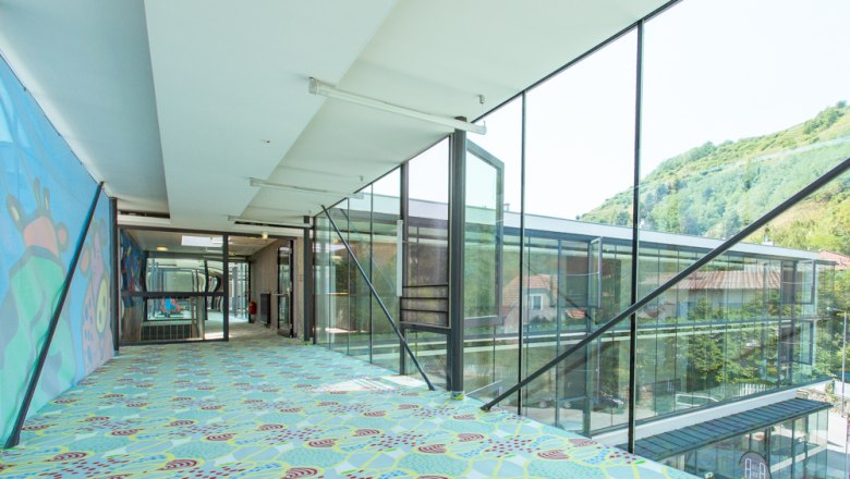 Durchgang Turmstudios, © arte Hotel Krems Moderner, verglaster Durchgang mit buntem Teppich und Wandkunst.