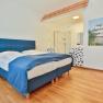 Hotel Unter den Linden Zimmer 204, © Hotel Unter den Linden Hotelzimmer mit blauem Bett, Holzboden und offener Dusche.