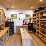 Regional Laden, © Familie Hofbauer Innenansicht eines kleinen, gemütlichen Ladens mit Holzregalen, gefüllt mit regionalen Produkten wie Wein, Marmelade und Gemüse.