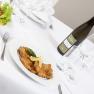 Gedeckter Tisch mit Schnitzel, Salat und Weinflasche.