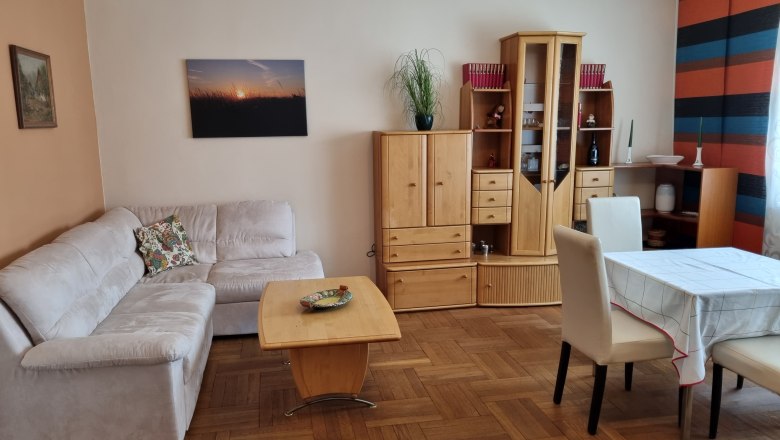 Living room with beige couch, wooden furniture and dining table.
