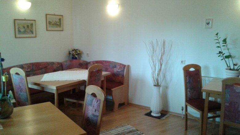 &Uacute;tuln&eacute; posezen&iacute; ve společn&eacute; kuchyni s dřevěn&yacute;mi stoly a čalouněn&yacute;mi židlemi.