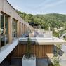 Moderne Spa-Terrasse mit Holzverkleidung und Blick auf bewaldete Hügel.