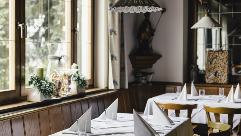 Innenansicht eines gemütlichen Restaurants mit gedeckten Tischen und Holzstühlen.