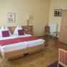 Hotelzimmer mit Doppelbett, Holzmöbeln und roten Akzenten.
