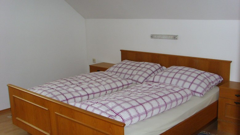 Schlafzimmer mit Holzbett und kariertem Bettzeug.