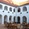 Innenhof des Eisenhuthauses mit Arkaden und Holzmöbeln.