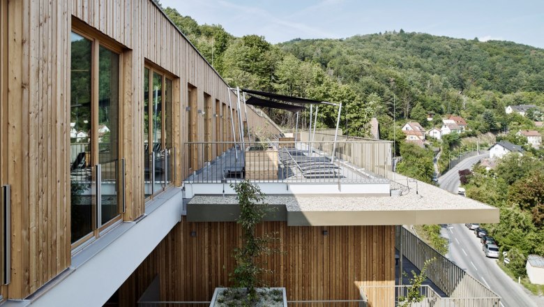 Moderne Spa-Terrasse mit Holzverkleidung und Blick auf bewaldete Hügel.