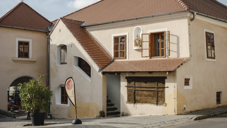 Historisches Gebäude mit roten Ziegeldächern und offenen Fenstern.