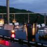 Abendliche Terrasse mit Kerzenlicht, Weingläsern und Blick auf eine Stadt.