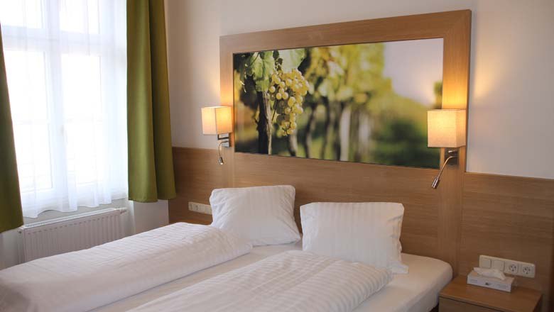 Ein gemütliches Gästezimmer mit zwei Einzelbetten, einem großen Bild von Weintrauben über dem Bett und zwei Wandlampen.