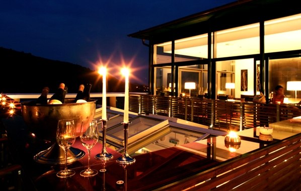Abendliche Restaurantterrasse mit Kerzenlicht und Weingläsern.