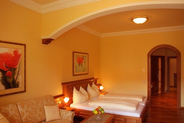 Gemütliches Hotelzimmer mit Doppelbett, Sofa und Gemälden an den Wänden.