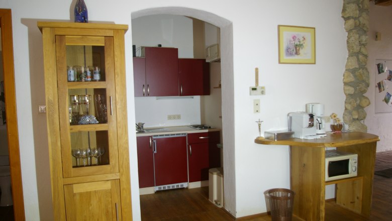 Kleine K&uuml;che mit Holzm&ouml;beln, roten Schr&auml;nken und Kaffeemaschine.