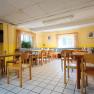 A bright breakfast room with wooden furniture, yellow walls and large windows.