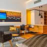 Modern&iacute; hotelov&eacute; apartm&aacute; s pohovkou, křeslem, TV a kuchyňsk&yacute;m koutem.