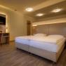 Modernes Hotelzimmer mit Doppelbett, Schreibtisch, Stuhl und Fernseher.