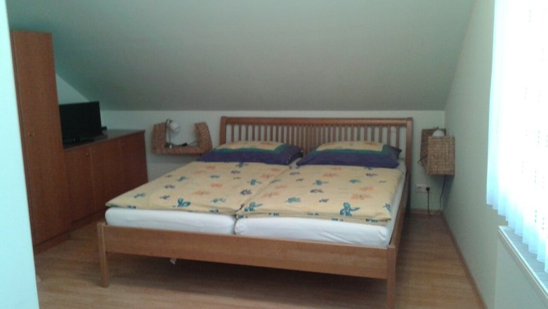 Ein Schlafzimmer mit einem Doppelbett, einem Schrank und einem Fernseher auf einem Schrank.