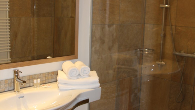 Modern bathroom with washbasin, mirror and shower.