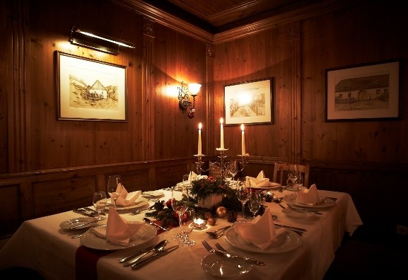 Festlich gedeckter Tisch in einer gem&uuml;tlichen Weinstube mit Kerzenlicht und Holzw&auml;nden.