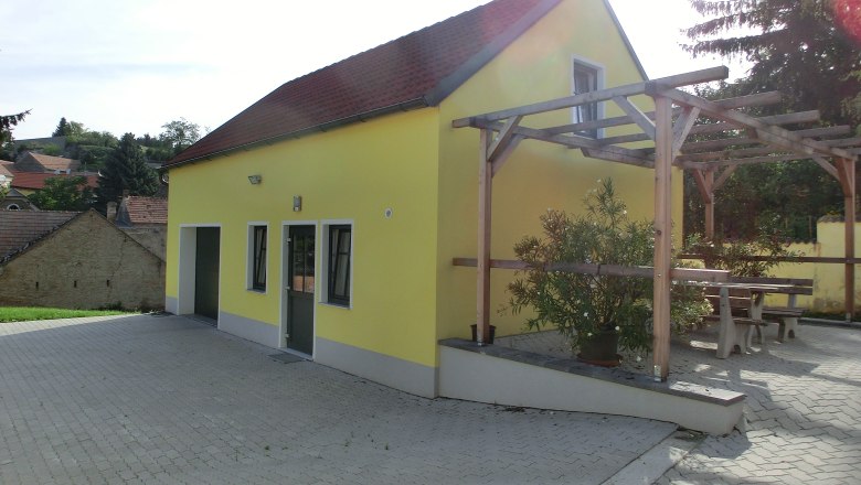 Yellow building with red roof and pergola outside.