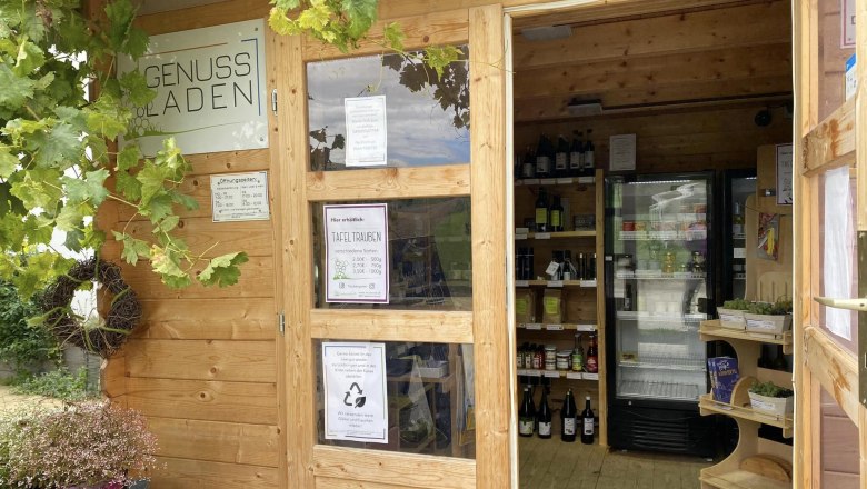 Ein kleiner Holzladen mit Weintrauben und Getränken im Inneren.