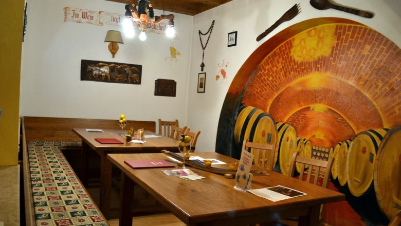 Gem&uuml;tliche Stube der L&ouml;ssiade mit Holztischen, warmem Licht und traditioneller Einrichtung.