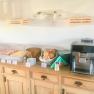 Frühstücksbuffet mit Aufschnitt, Brötchen und Kaffeemaschine auf einem Holztisch.