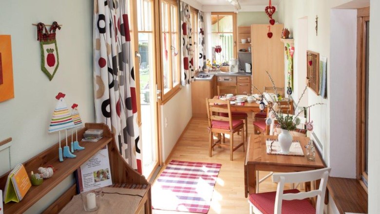 Gemütliche Ferienwohnung mit Holzmöbeln, Esstisch und dekorativen Vorhängen.