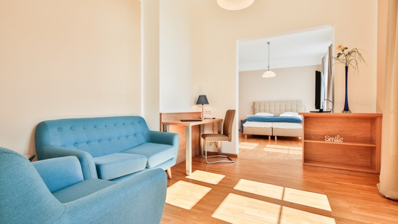Helles Hotelzimmer mit blauen Möbeln und Doppelbett.