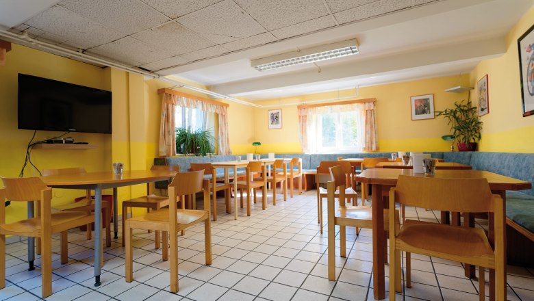 A bright breakfast room with wooden furniture, yellow walls and large windows.