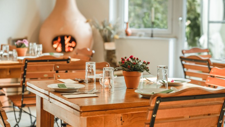 &Uacute;tuln&aacute; sn&iacute;daňov&aacute; m&iacute;stnost s dřevěn&yacute;mi stoly a židlemi, prostřen&yacute;mi n&aacute;dob&iacute;m a sklenicemi. Hřejivou atmosf&eacute;ru vytv&aacute;ř&iacute; krb v pozad&iacute;.