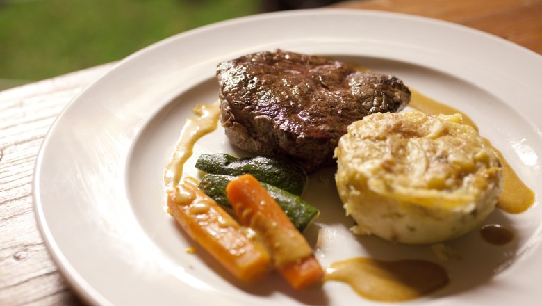 A plate with a piece of meat, vegetables and a potato side dish.