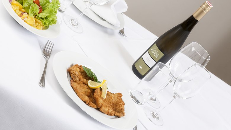Gedeckter Tisch mit Schnitzel, Salat und Weinflasche.