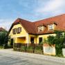 Gelbes Landhaus mit rotem Ziegeldach und Garten.